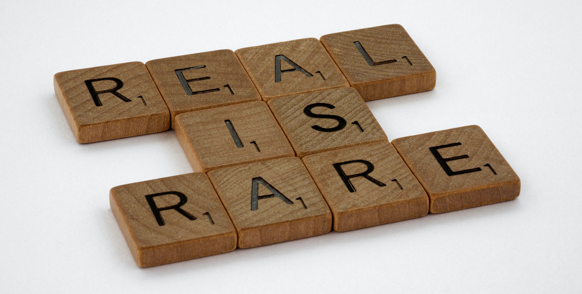 Small wooden cubes with letters that together spell out the phrase 'Real is Rare'.